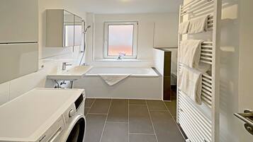 Ein modernes Badezimmer mit integrierter Waschmaschine, Waschbecken und einem Fenster mit Blick.