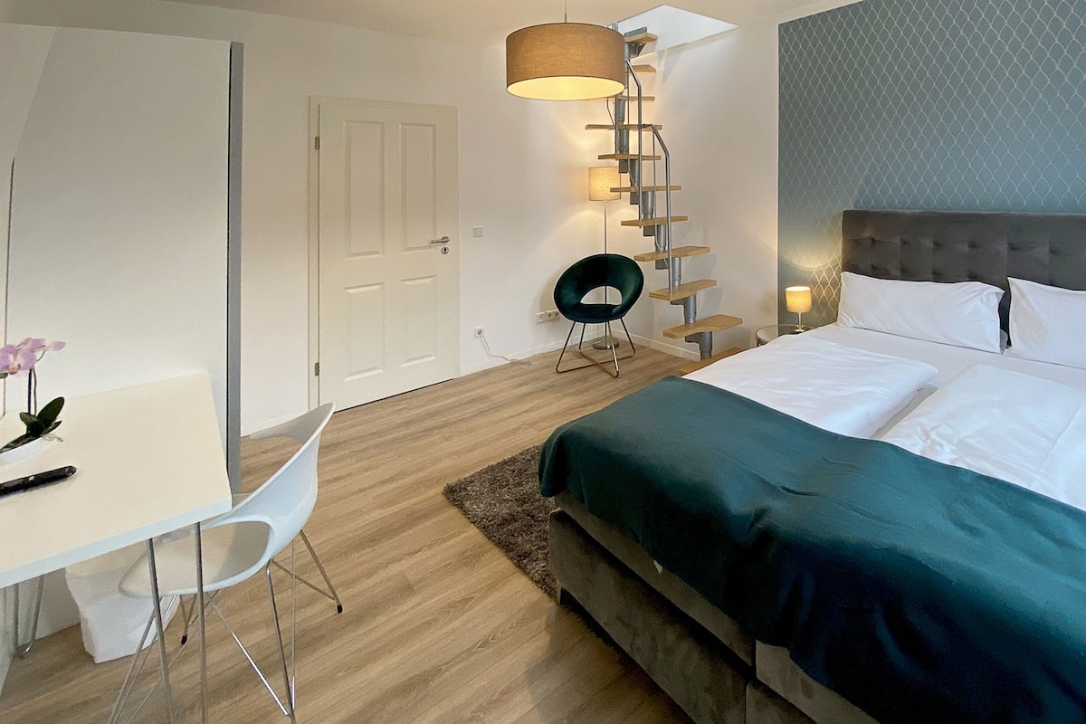 A modern hotel room with a bed, a desk, and a chair.