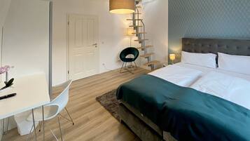 A modern hotel room with a bed, a desk, and a chair.