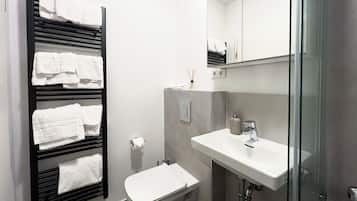 Un baño moderno con toallero negro, inodoro blanco y cabina de ducha de vidrio.