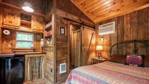 A cozy cabin interior with a bed, a small kitchenette, a wooden ceiling, and a window. - The Owl's Perch - Backwoods glamping cabin over amazing creek (Robbinsville)
