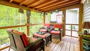 A wooden deck with wicker furniture, a sign reading "RELAX," and a view of a forest. - The Owl's Perch - Backwoods glamping cabin over amazing creek (Robbinsville)