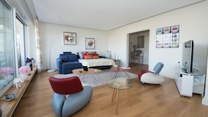 A modern living room with a sofa, armchairs, a coffee table, and a TV. - Schloesing, 16e Tour Eiffel, Luxueux pied à terre (Paris)