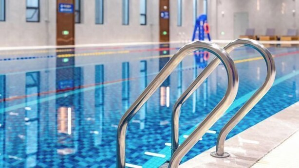 A swimming pool with clear blue water, metal poolside railings, and a modern interior design with large windows. - Rendezvous Hotel (CHANGZHI)