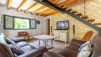 A living room with a brown leather sofa, a white coffee table, and a stone wall.