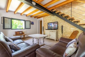 A living room with a brown leather sofa, a white coffee table, and a stone wall. - Heated pool, jacuzzi, vineyard views. Walk to restaurant, market, wine tasting. (Monbazillac)