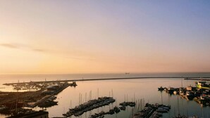 Ein Yachthafen mit vertäuten Booten, eine Pier, die sich ins Wasser erstreckt, und Gebäude entlang des Ufers.