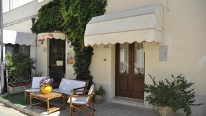 A café with outdoor seating, a covered entrance, and potted plants. - La Caribena (San Vito Lo Capo)