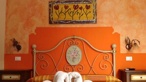 A bed with a metal headboard, a floral wall hanging above, and two nightstands with decorative items. - La Caribena (San Vito Lo Capo)