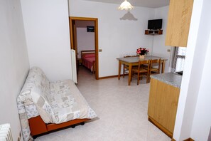 Une pièce de taille modeste comprenant un lit, une petite table à manger et un coin cuisine.
