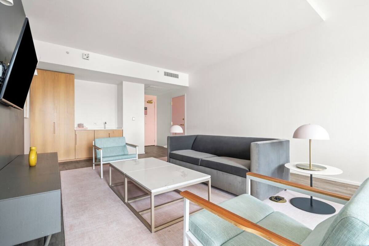 Una sala de estar moderna con un sofá, una mesa de centro, un televisor y una lámpara.