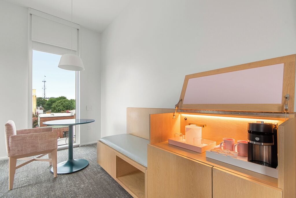 A compact kitchenette with a built-in coffee maker, a small table, and a bench.