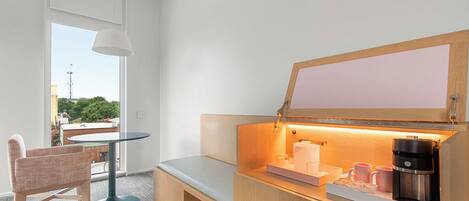 A compact kitchenette with a built-in coffee maker, a small table, and a bench.