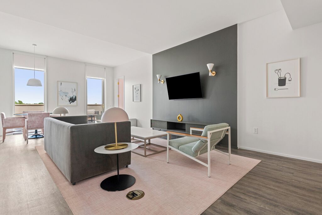 A modern living room with a grey sofa, a round coffee table, and a TV mounted on the wall.