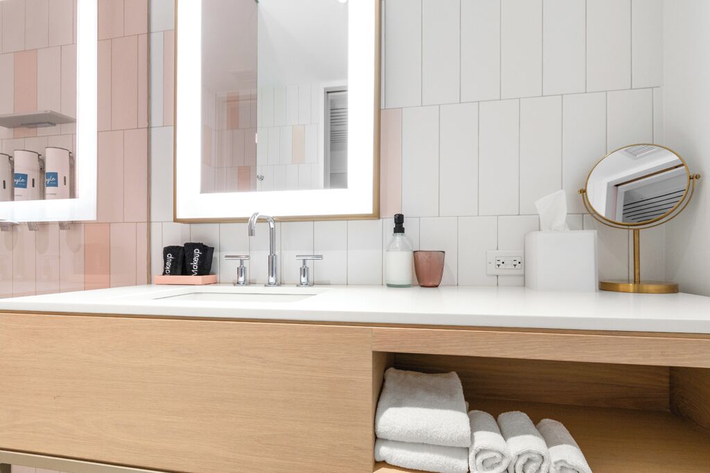 A modern bathroom with a large mirror, a sink, and a towel rack.
