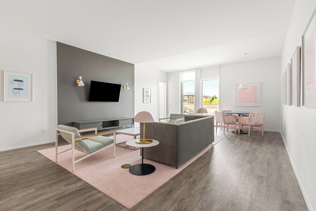 A modern living room with a sofa, a TV, and a dining area with chairs and a table.