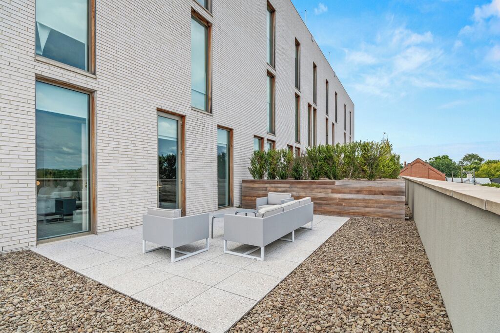 A modern building with a patio area featuring outdoor seating and a landscaped garden.