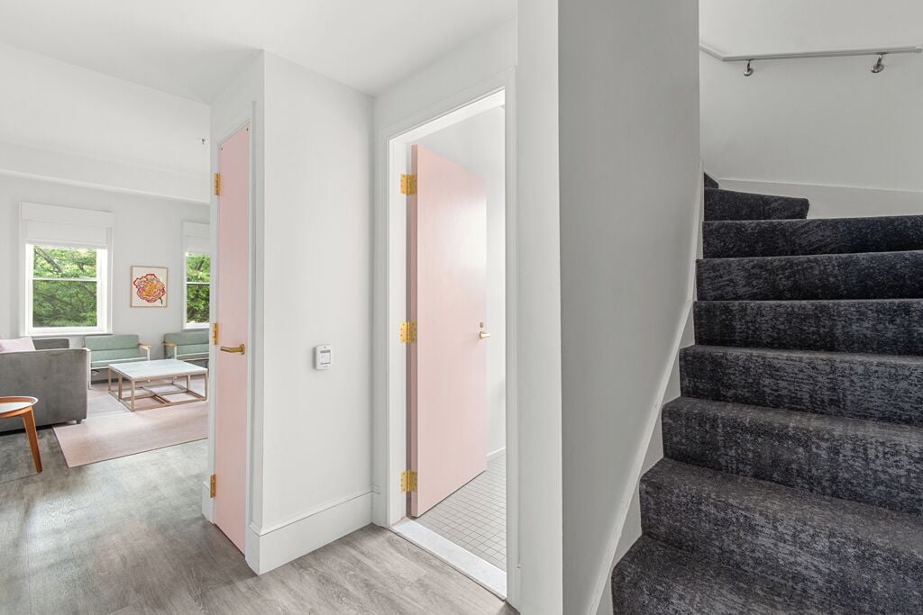 A modern interior with a staircase, a living area with a sofa and coffee table, and a door leading to another room.