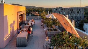 Een terras op het dak met buiten zitplaatsen, een bar en uitzicht op de stad.