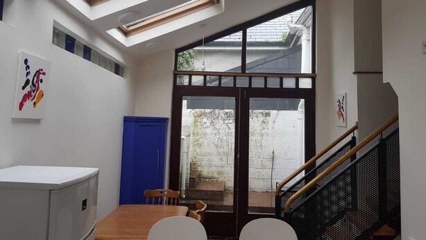 Una habitación pequeña con tragaluz, zona de comedor y escalera.