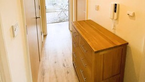 A hallway with a wooden dresser, a telephone, and a wall-mounted light fixture. - Golden Heights 7 (Maidstone)