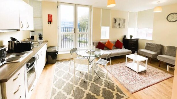 A modern apartment with a kitchen, dining area, and living room. It features a balcony with a view, a sofa, and a coffee table. - Golden Heights 7 (Maidstone)