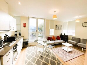 Un appartement moderne comprenant une cuisine, un coin repas et un salon. Il dispose d’un balcon avec vue, d’un canapé et d’une table basse.