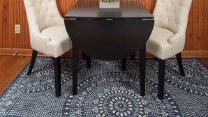 Un salón de conferencias con una mesa negra, dos sillas color beige, una planta en maceta y un televisor de pantalla plana grande montado en la pared.