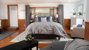 Un dormitorio con una cama grande, una mesita de noche, una silla, un escritorio, un aparador y una ventana con cortinas.