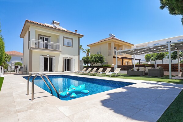 Una casa de dos pisos con piscina, un balcón y un patio cubierto.