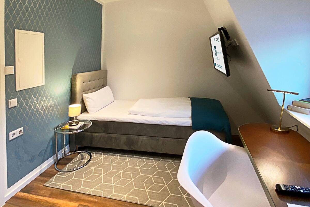 Una habitación de hotel moderna con cama, escritorio, silla y una mesita.