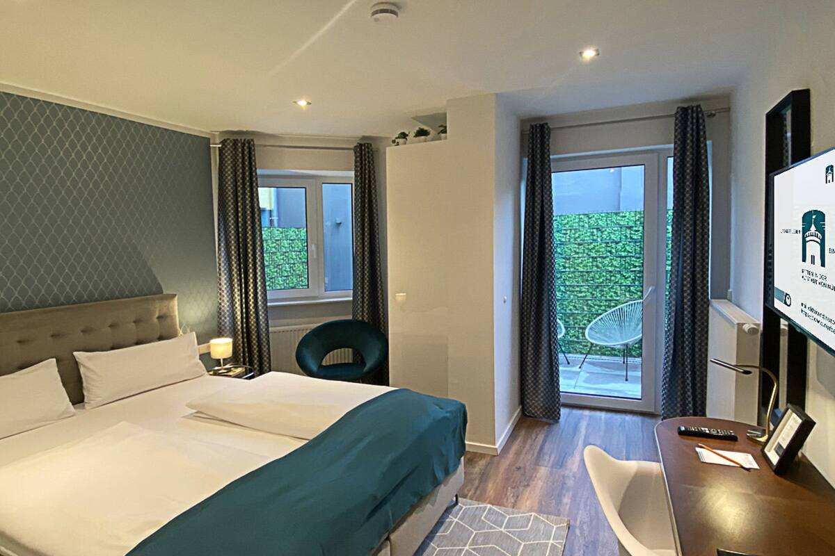 Una habitación de hotel con una cama grande, un escritorio y vistas al exterior.