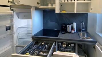 A modern kitchen with built-in appliances, a dishwasher, and a variety of utensils and cookware stored in a drawer.