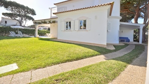 Un bâtiment blanc avec un toit recouvert de tuiles, un chemin pavé et une pelouse bien entretenue.