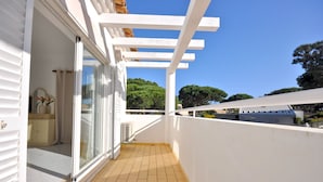 Un balcon doté d’une balustrade blanche, d’une porte-fenêtre coulissante et d’un sol carrelé.