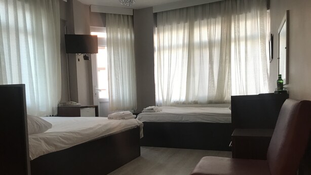 A hotel room with two beds, a desk, a chair, and a TV.