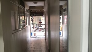 A corridor with tiled flooring, a ceiling with a light fixture, and a door on the right.