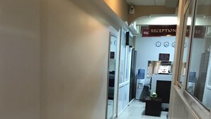 A hotel reception area with a reception desk, a clock, and a water dispenser.