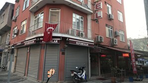 A red building with balconies, a flag, and a sign for a hotel.