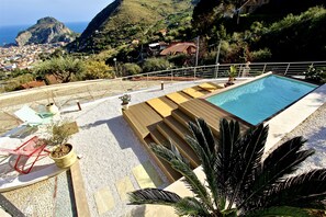 Een seizoensgebonden buitenzwembad en ligstoelen