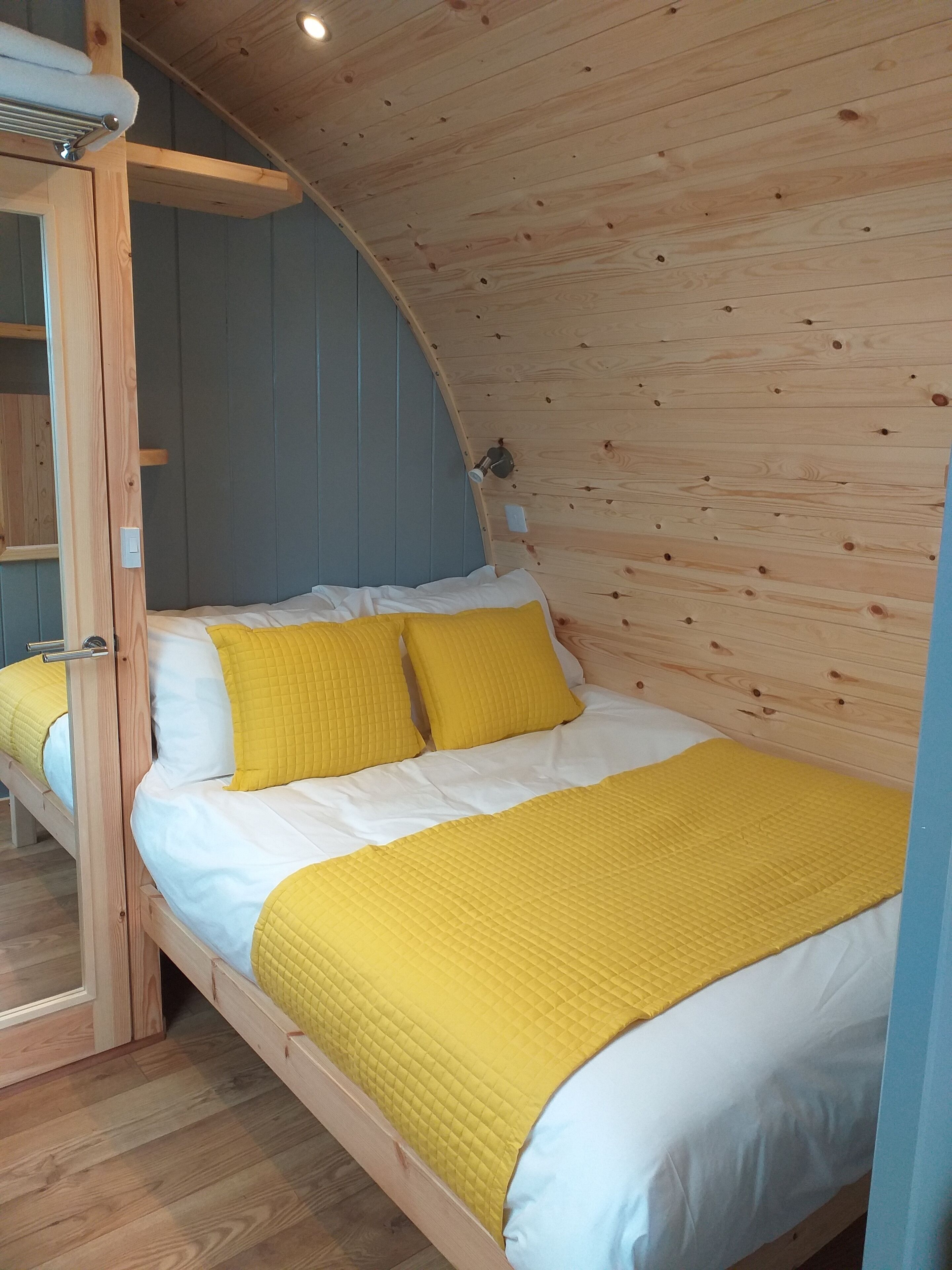 Una cama litera de madera con colchón acolchado amarillo y ropa de cama blanca.