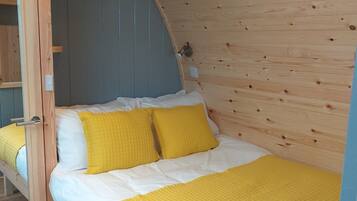 Una cama litera de madera con colchón acolchado amarillo y ropa de cama blanca.