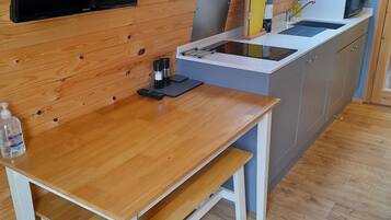 Cocina compacta con paredes de madera, televisor integrado, una pequeña mesa de comedor y un tragaluz.