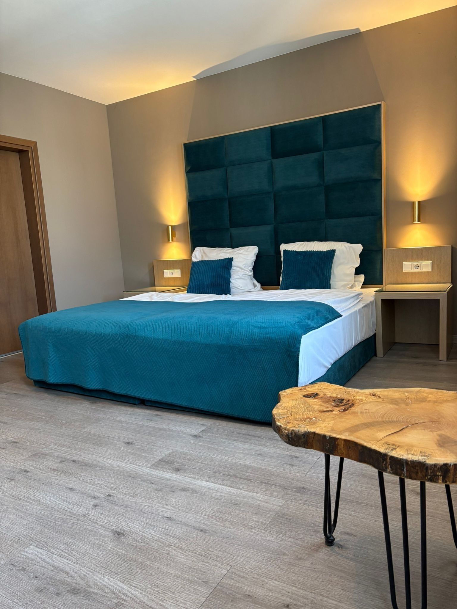 A modern bedroom with a large bed, two bedside tables, and a wooden coffee table.
