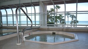 An indoor swimming pool with a view of the beach and palm trees.