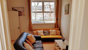 Una sala de estar con un sofá de cuero negro, un sofá amarillo y una mesa de centro blanca.