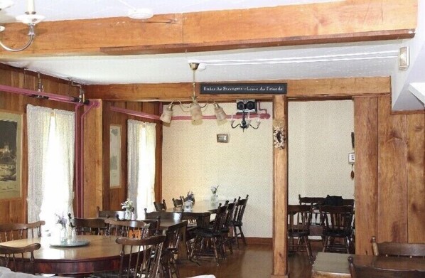 Un comedor con paredes de madera, una araña y un letrero sobre la puerta.