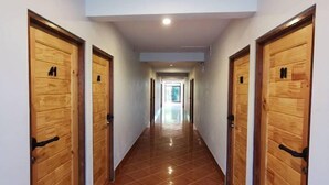 A long, narrow hallway with wooden doors on both sides, numbered 11 and 12, leading to a bright room at the end. - Pakarang Resort (La-ngu)
