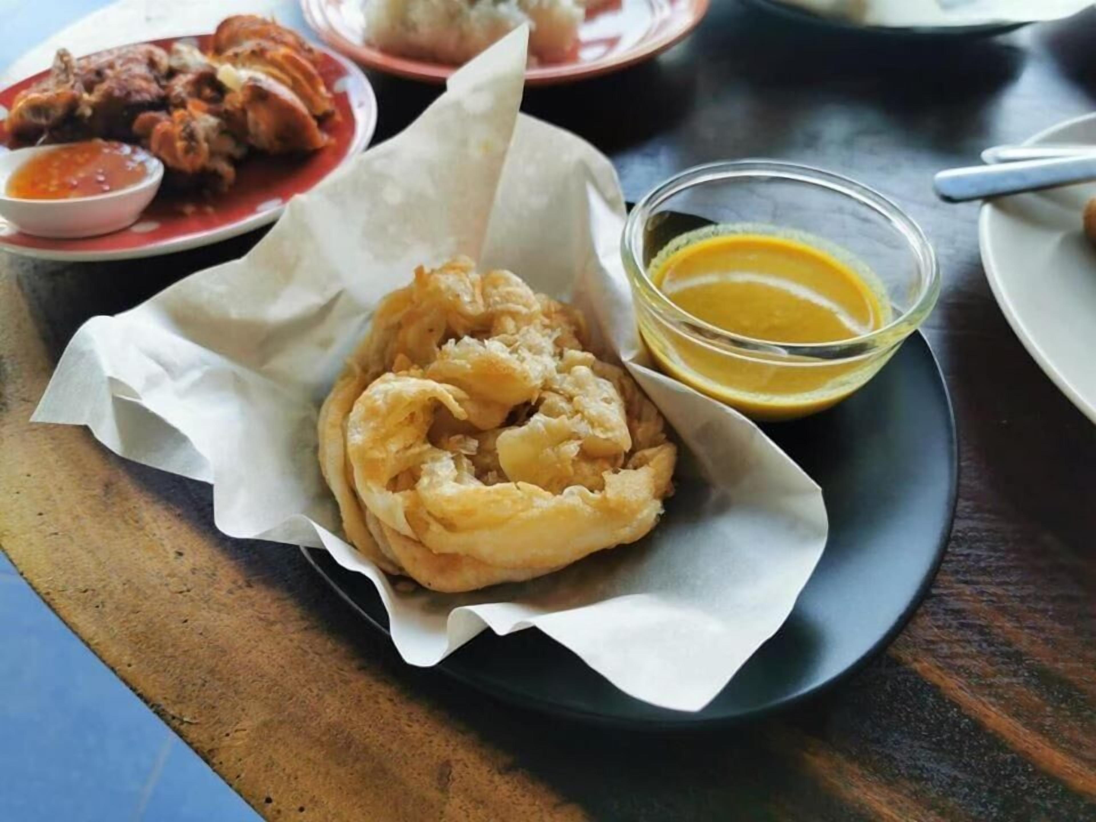 A plate with fried food and a small bowl of sauce.