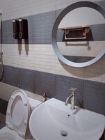 A bathroom with a white sink, a mirror, and two black soap dispensers on the wall.